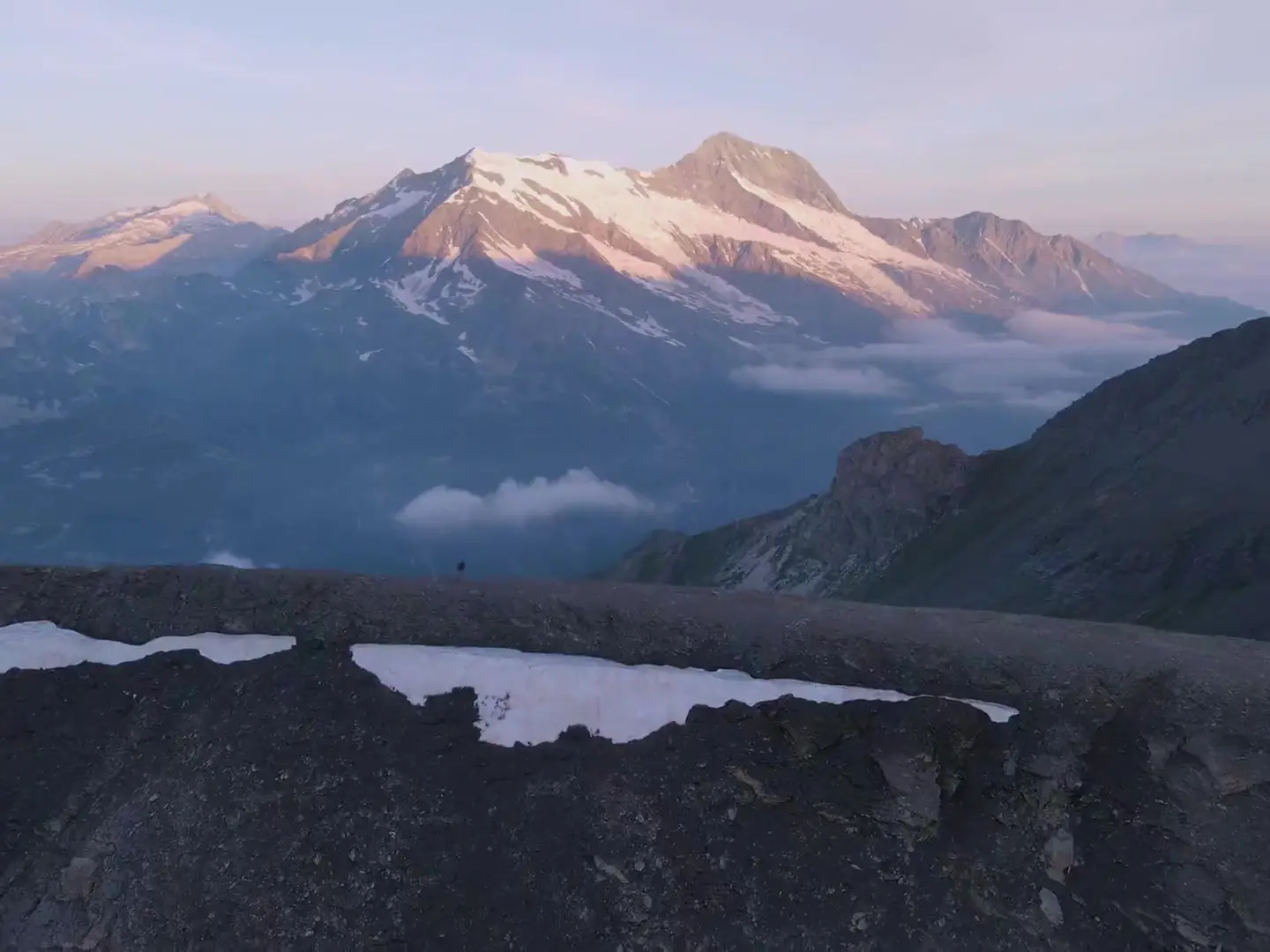 Crêtes enneigées des Alpes au lever du jour, mer de nuages dans la vallée.